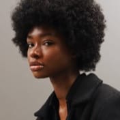 Headshot of a Black woman with an afro, wearing a black shirt.